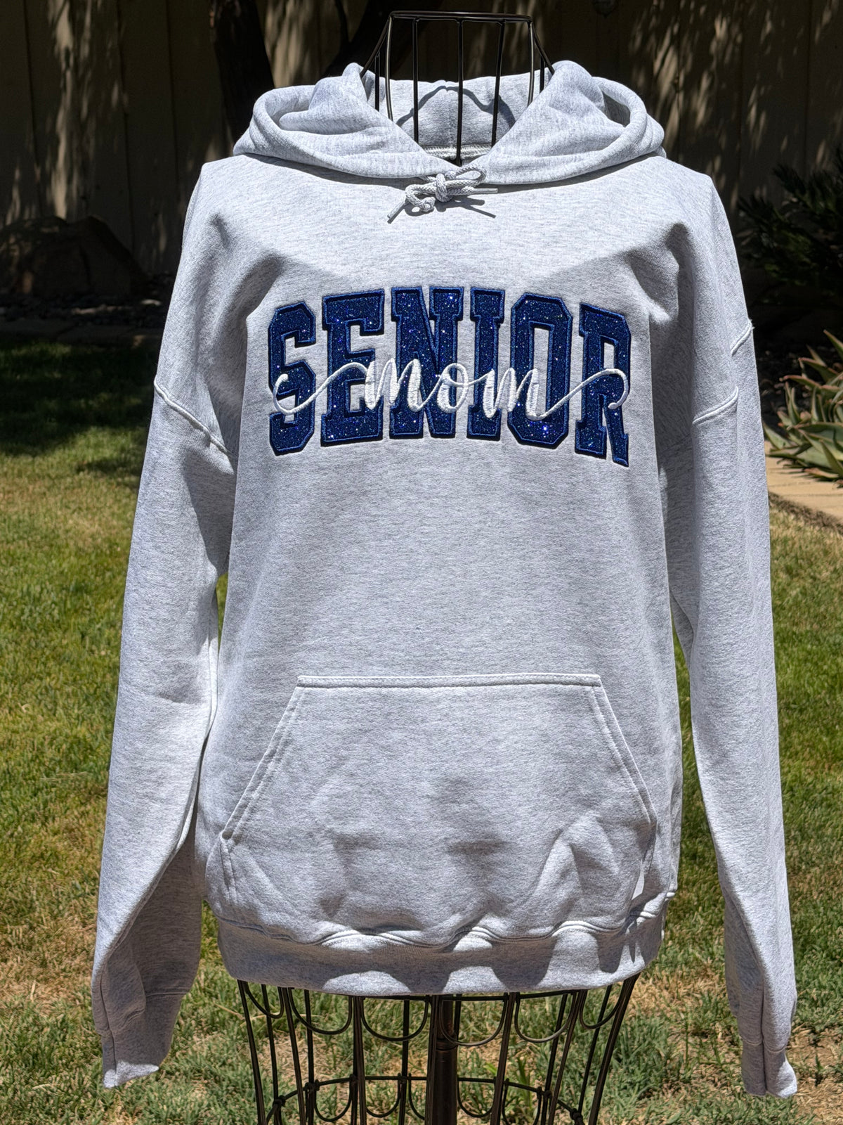 Gray Senior Mom embroidered hoodie featuring navy SENIOR lettering with white mom script across the front.